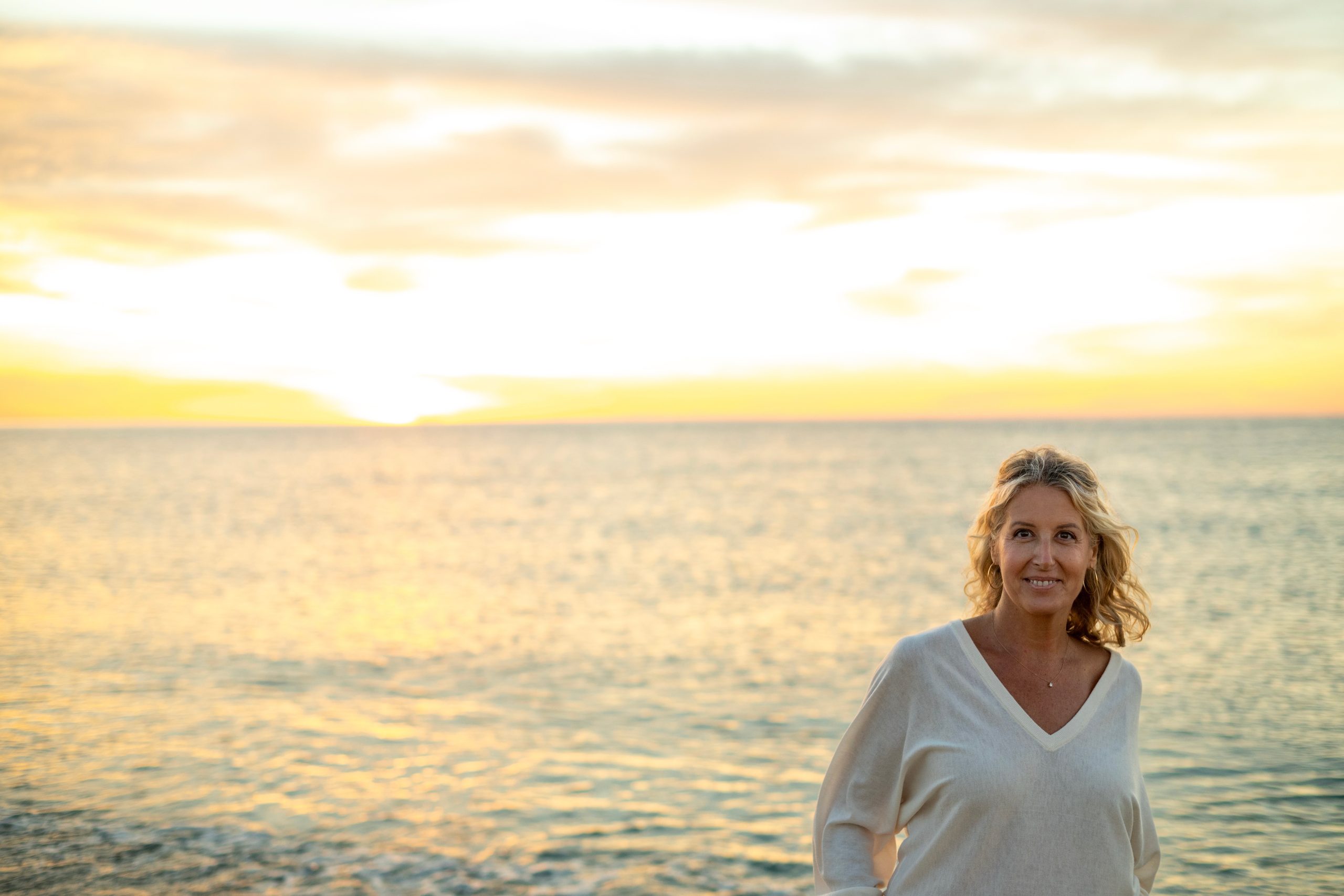Rebeca Falcó sonriendo frente al mar al atardecer